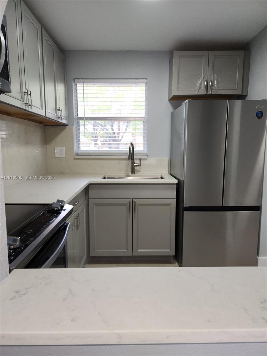 2811 North Pine Island Road, Unit 107 Sunrise, FL 33322 - Photo 2 of 16 a kitchen with a refrigerator sink and cabinets