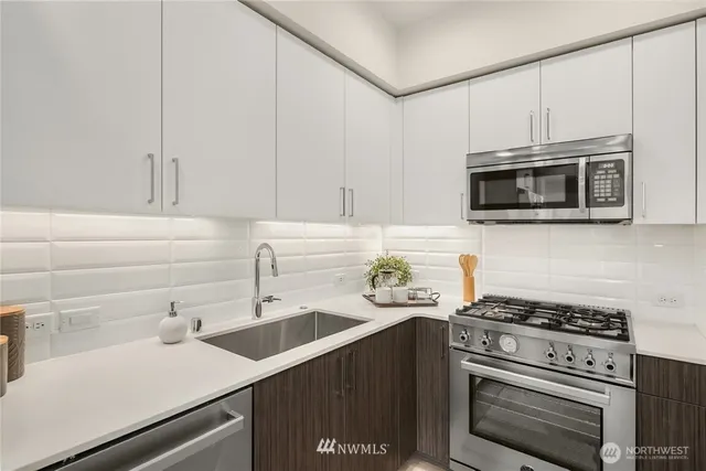 a kitchen with stainless steel appliances a sink dishwasher stove and microwave with wooden cabinets