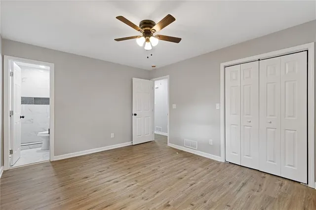 an empty room with wooden floor and ceiling fan