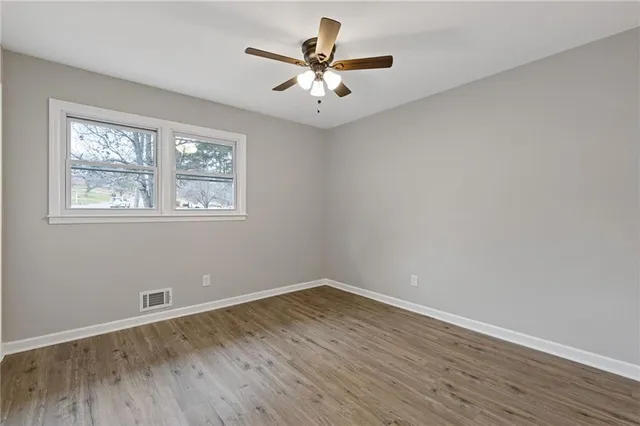 an empty room with wooden floor and ceiling fan