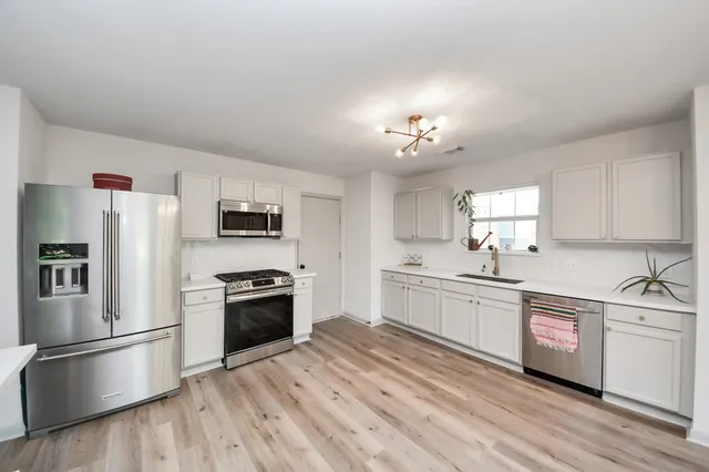 a kitchen with granite countertop a refrigerator stove a sink and dishwasher with wooden floor