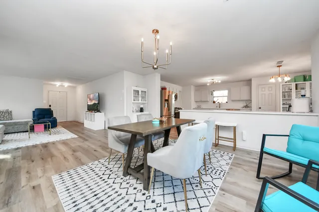 a living room with couches a dining table and kitchen view with wooden floor