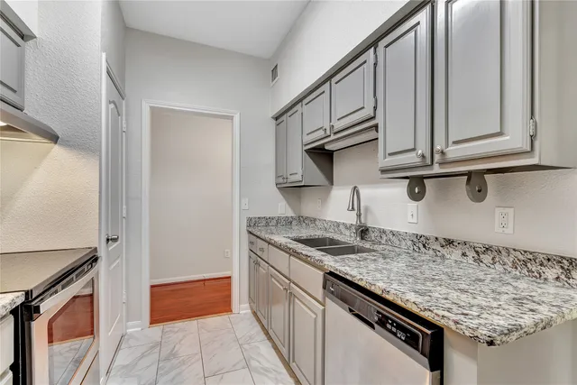 a kitchen with stainless steel appliances granite countertop a sink and a refrigerator