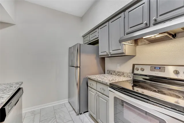 a kitchen with stainless steel appliances granite countertop a refrigerator and a stove