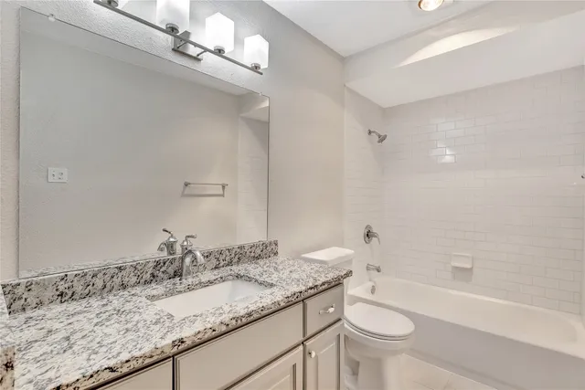 a bathroom with a granite countertop sink a toilet a mirror and bathtub