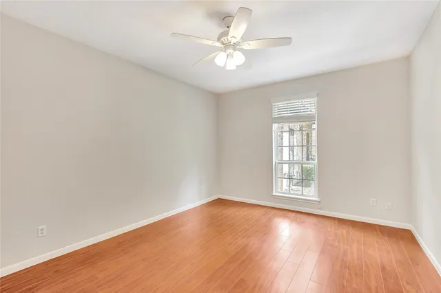 an empty room with wooden floor chandelier fan and windows