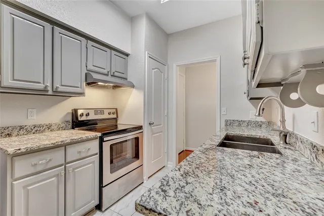 a kitchen with granite countertop a sink stainless steel appliances and cabinets