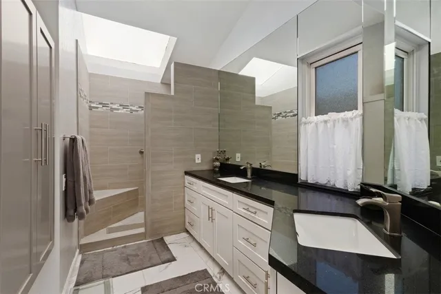 a bathroom with a granite countertop sink a mirror and a shower