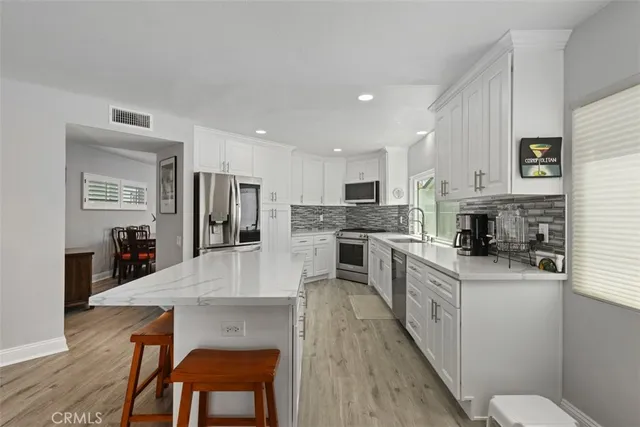 a kitchen with stainless steel appliances granite countertop a stove top oven a sink dishwasher a dining table and chairs with wooden floor