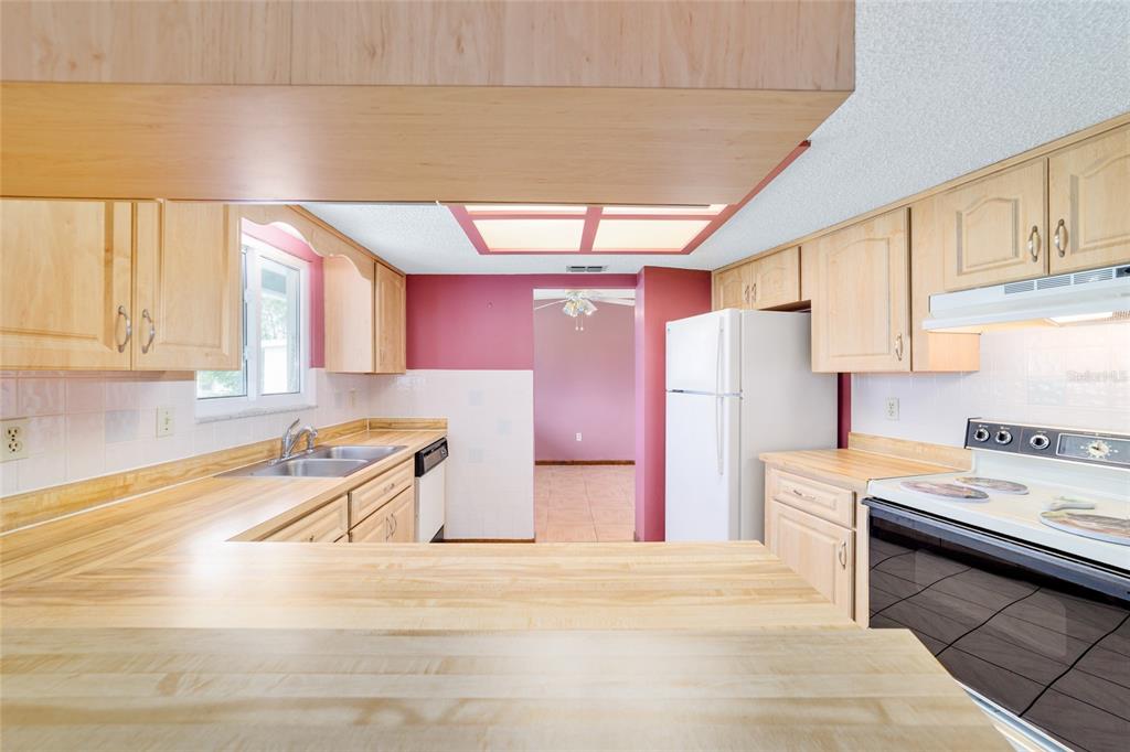 9841 Southwest 102nd Place Ocala, FL 34481 - Photo 29 of 66 a kitchen with a refrigerator a stove a sink dishwasher and wooden cabinets with wooden floor
