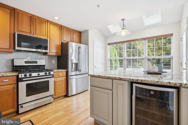 a kitchen with stainless steel appliances granite countertop a stove a sink dishwasher a refrigerator and a microwave