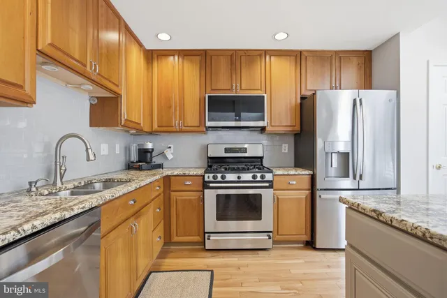 a kitchen with stainless steel appliances granite countertop a stove a sink and a refrigerator