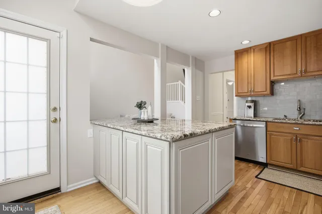 a kitchen with stainless steel appliances granite countertop a sink and cabinets with wooden floor