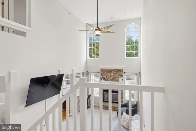 a view of an empty room with wooden floor and a ceiling fan