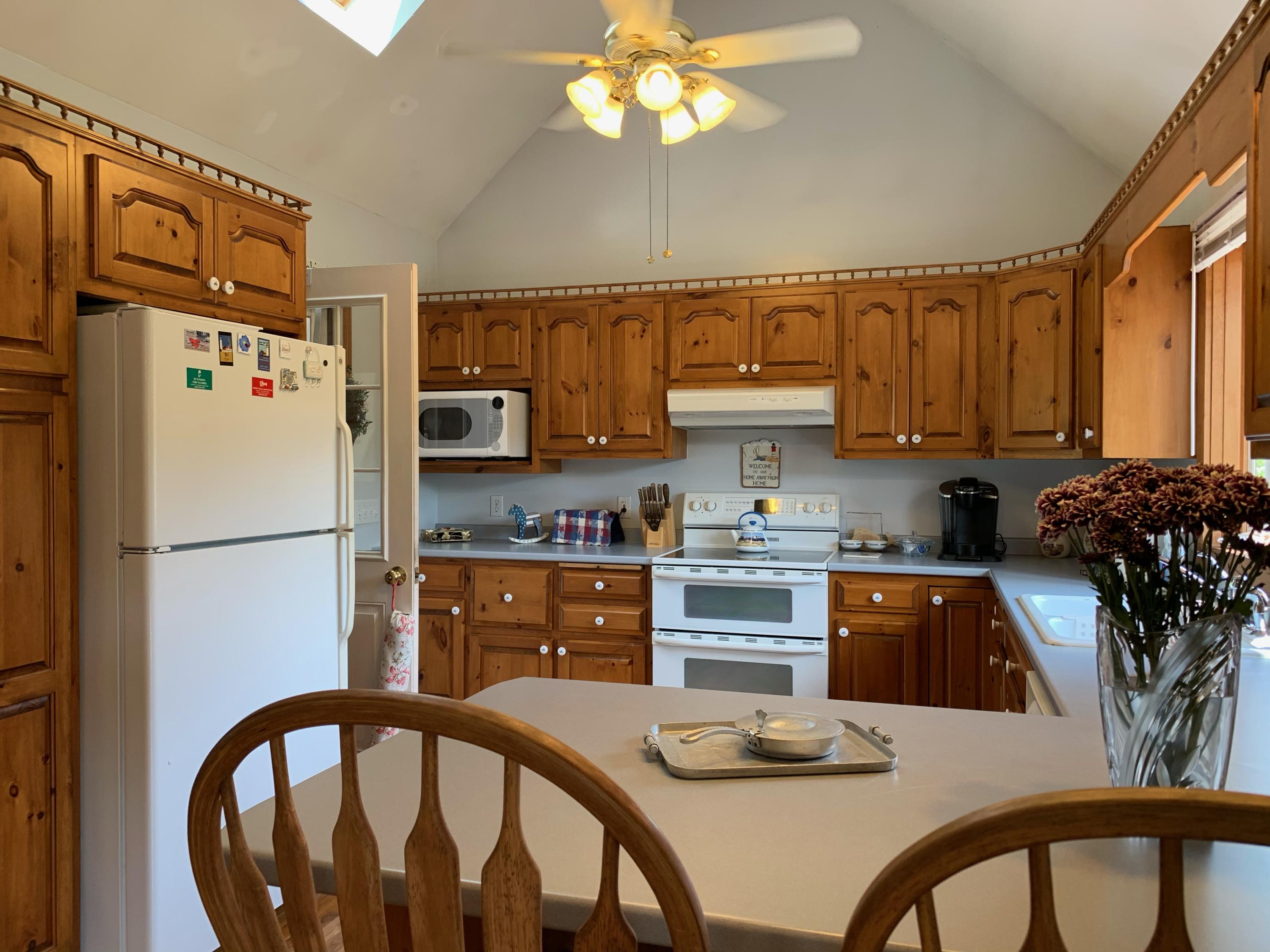 90 Jennie Clark Road Eastham, MA 02642 - Photo 4 of 35 a kitchen with stainless steel appliances granite countertop a refrigerator a stove a sink dishwasher and white cabinets with wooden floor