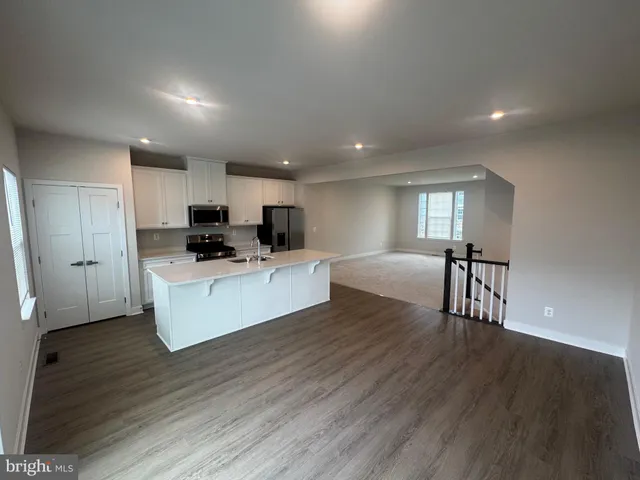 a view of kitchen with microwave a refrigerator and wooden floor