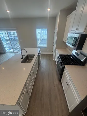 a kitchen with stainless steel appliances a sink a stove top oven a counter space and cabinets