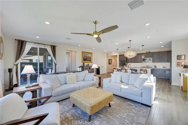a living room with furniture kitchen view and a wooden floor