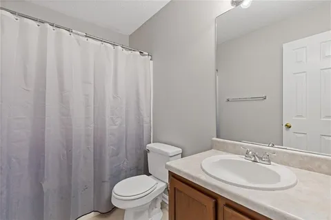 a bathroom with a granite countertop sink and a toilet