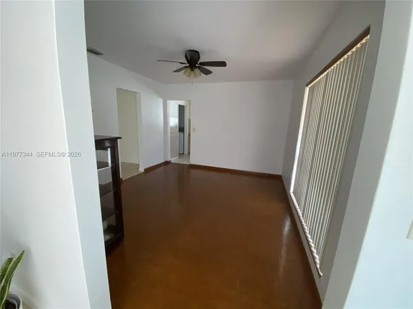 a view of an empty room with wooden floor and a ceiling fan