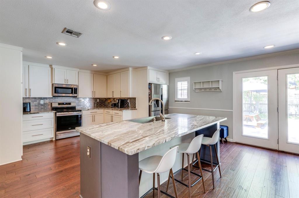 3605 Merrell Road Dallas, TX 75229 - Photo 16 of 25 a kitchen with granite countertop kitchen island wooden floor and stainless steel appliances