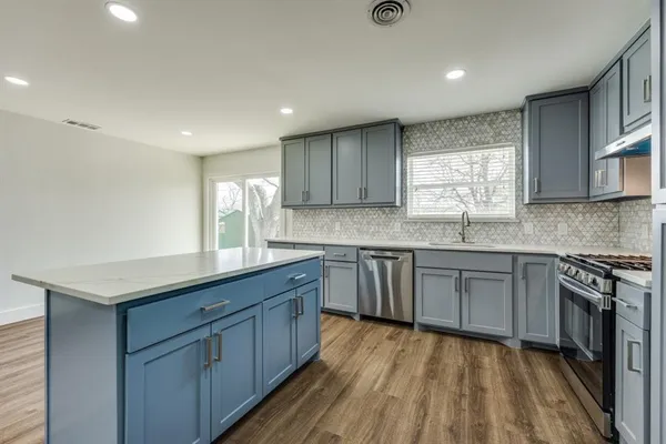 a kitchen with granite countertop a sink cabinets stainless steel appliances and a window