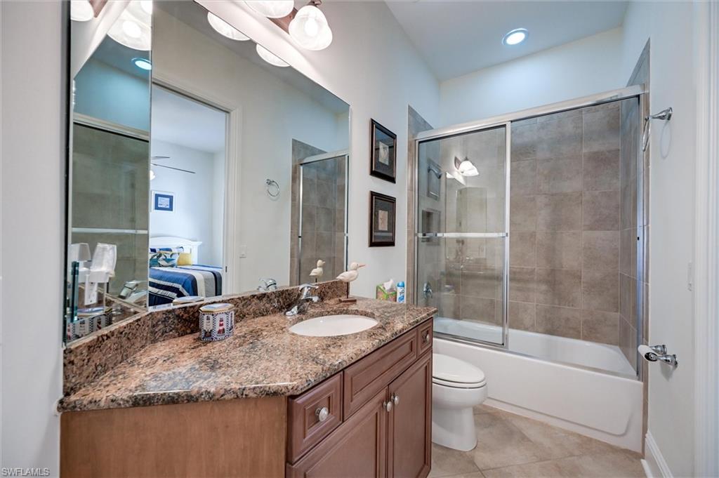 7587 Moorgate Point Way Naples, FL 34113 - Photo 42 of 50 Bathroom featuring a single vanity with stone countertop, integrated sink, and wood-finish cabinetry