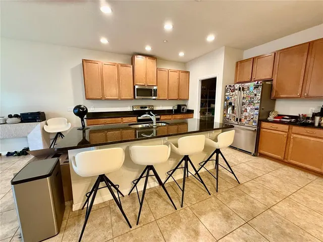 a kitchen with stainless steel appliances granite countertop a table chairs sink and cabinets