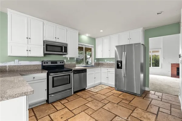 a kitchen with stainless steel appliances granite countertop a refrigerator sink and stove