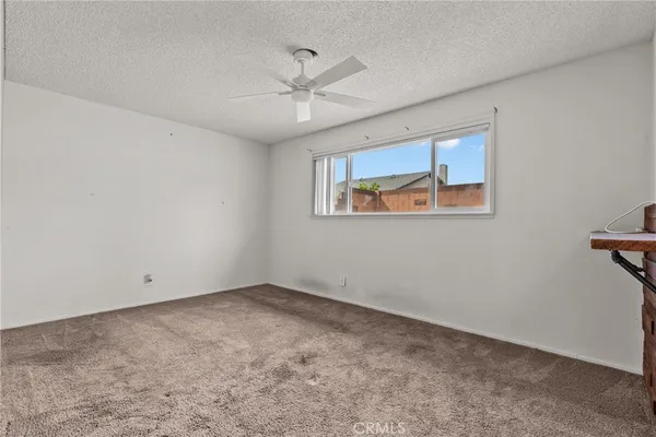 an empty room with a window and a fan