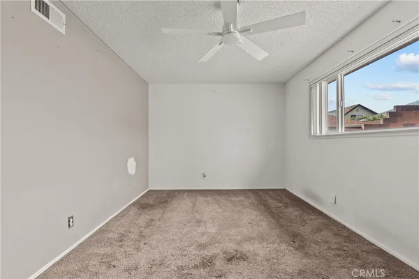 an empty room with a window and a ceiling fan