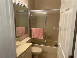 a bathroom with a granite countertop bathtub shower sink vanity and toilet