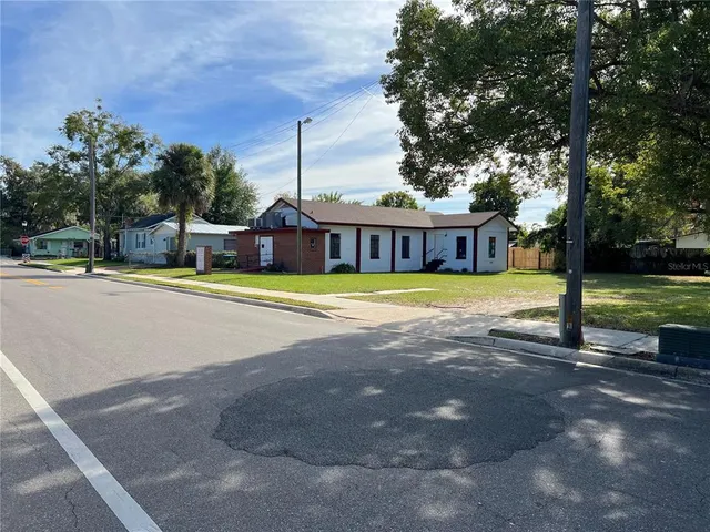 a view of a swimming pool with a patio and a yard with palm trees