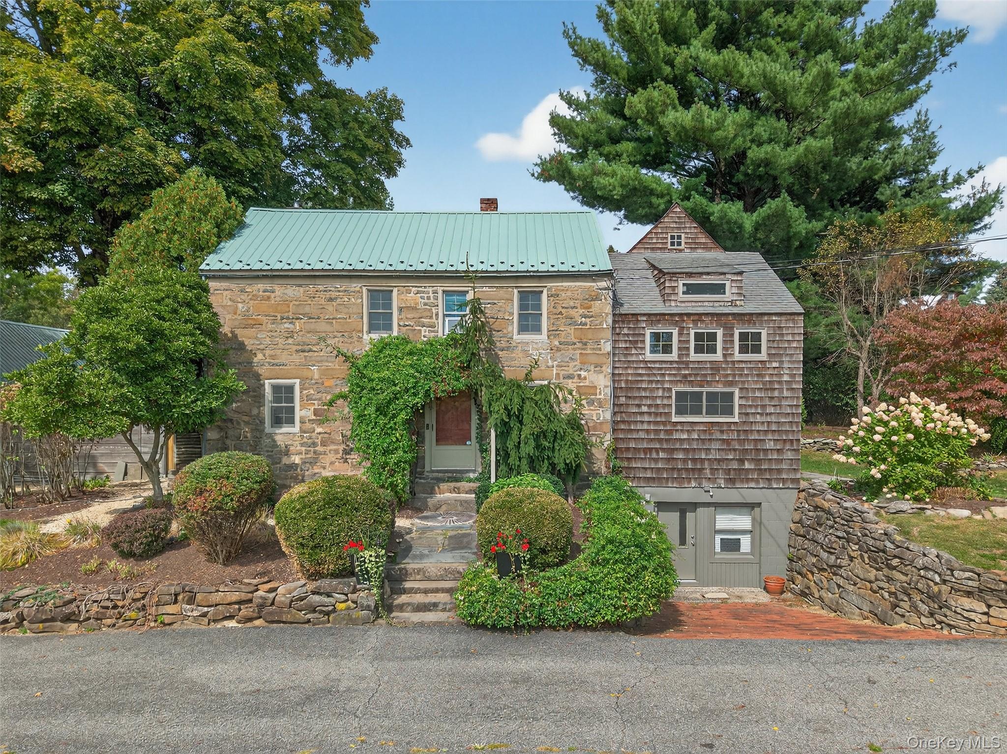 View of front of home with a chimney, a metal roof, and stone siding