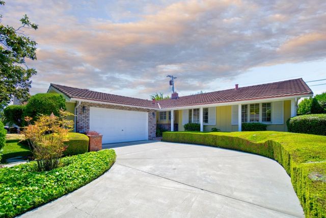 a front view of a house with a yard and potted plants