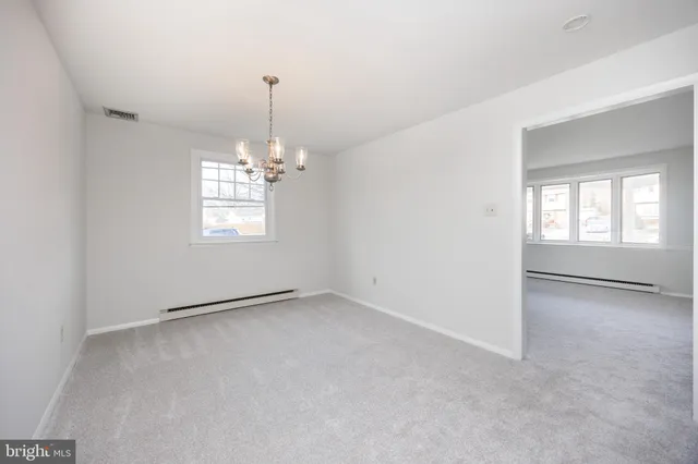 an empty room with chandelier fan and windows