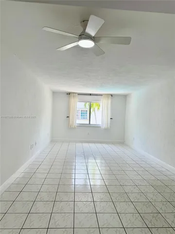an empty room with windows and ceiling fan