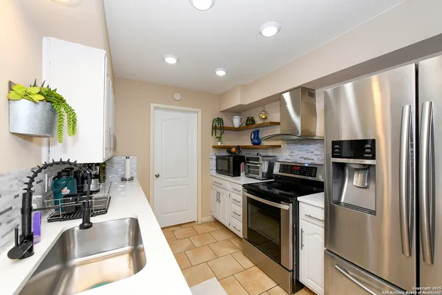 a kitchen with stainless steel appliances granite countertop a refrigerator a stove and a sink with wooden floor