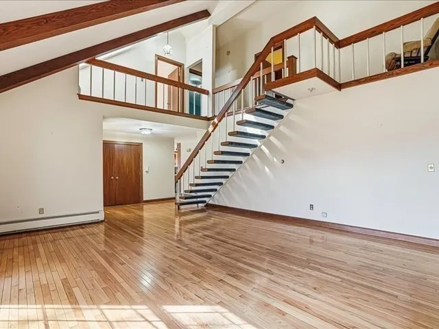 a view of a hallway with wooden floor and stairs
