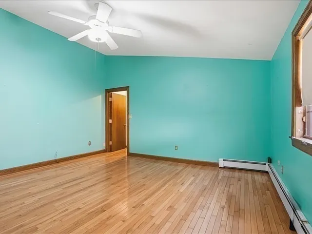 an empty room with wooden floor closet and windows