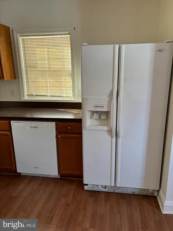 a kitchen with a refrigerator a stove and wooden floor