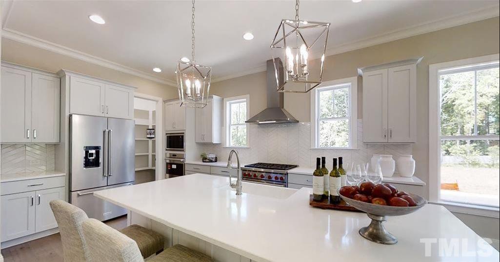 3013 Eden Harbor Court Raleigh, NC 27613 - Photo 7 of 11 a kitchen with stainless steel appliances a chandelier a refrigerator a stove a sink a dining table and chairs