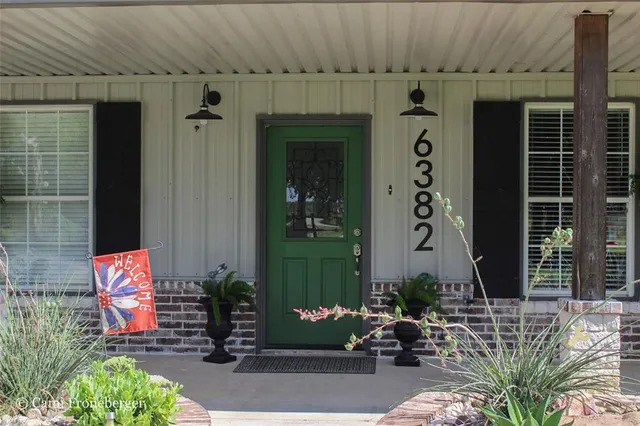a front view of a house with a garden and trees