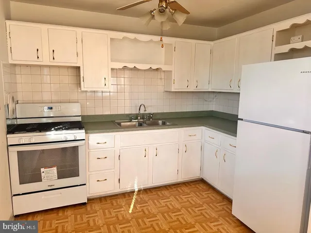 a kitchen with granite countertop white cabinets white stainless steel appliances and a sink