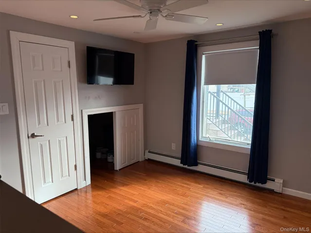 an empty room with wooden floor a ceiling fan and a window