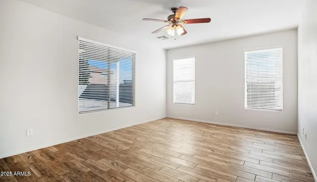 a view of empty room with wooden floor and fan