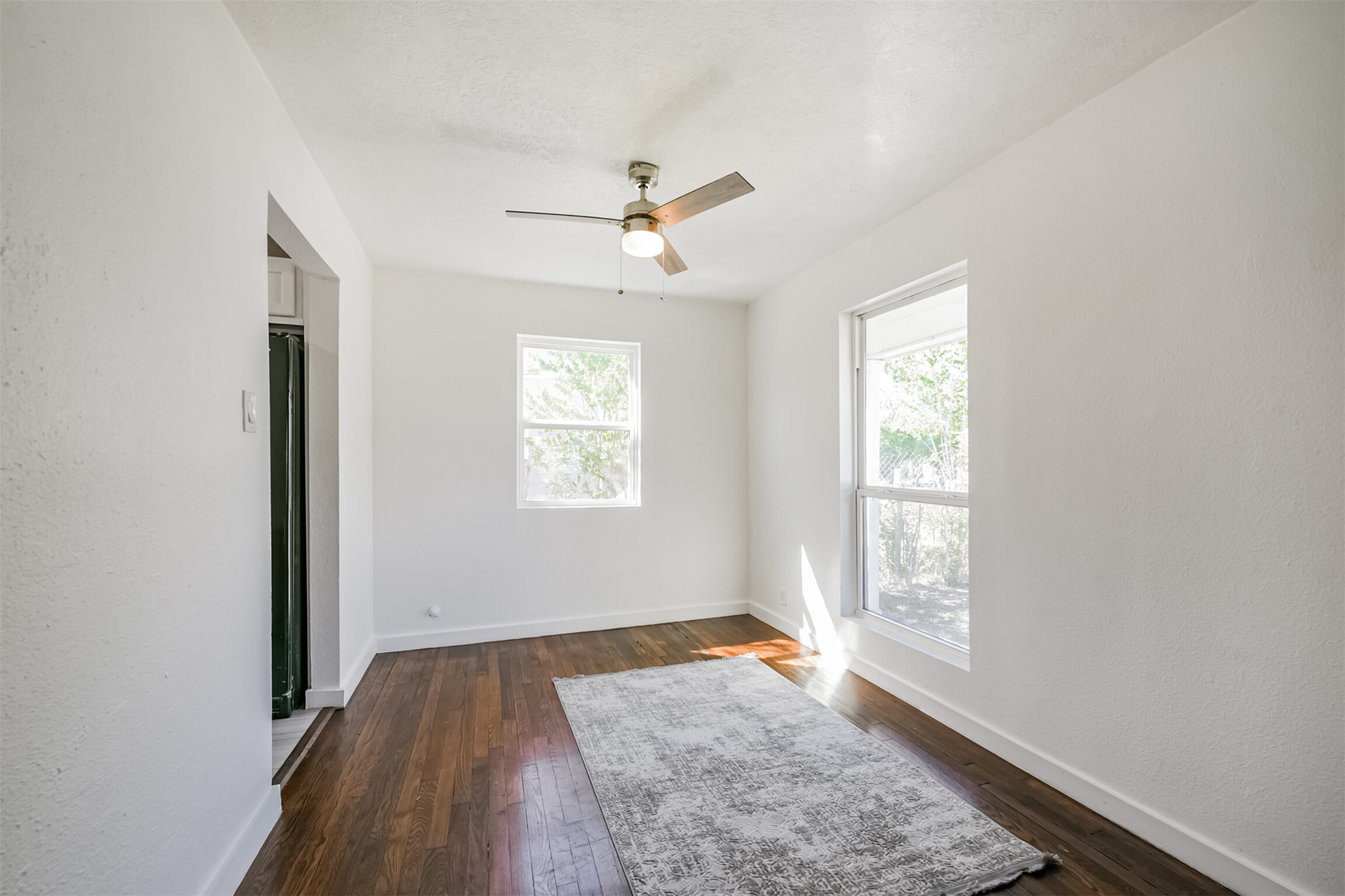 7546 Greendowns Street Houston, TX 77087 - Photo 11 of 33 an empty room with wooden floor ceiling fan and windows
