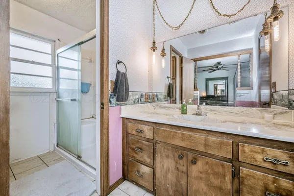 a bathroom with a granite countertop sink a mirror and a shower