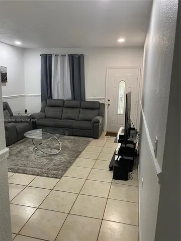 a living room with a black white checkered floor with a sink and a stove top oven