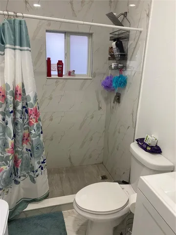 a bathroom with a toilet a sink and a shower curtain